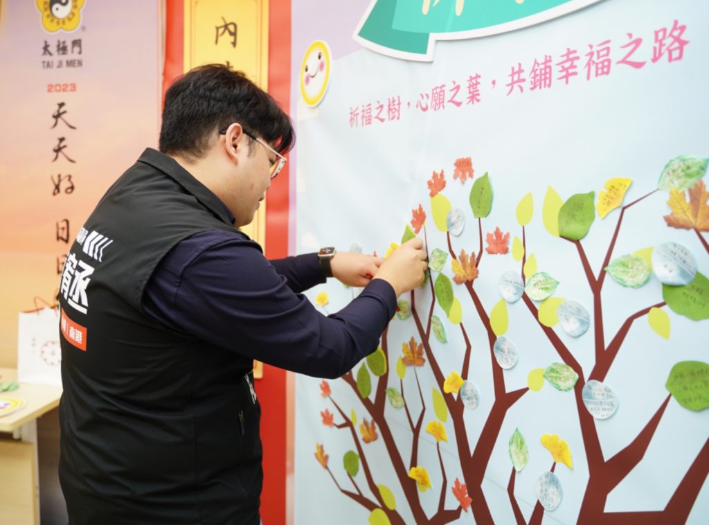 ▲臺北市議員陳宥丞服務處主任羅陳政佑將心願卡之葉貼在祈福之樹上,為2024年獻上滿滿祝福。(記者李欣翻攝)