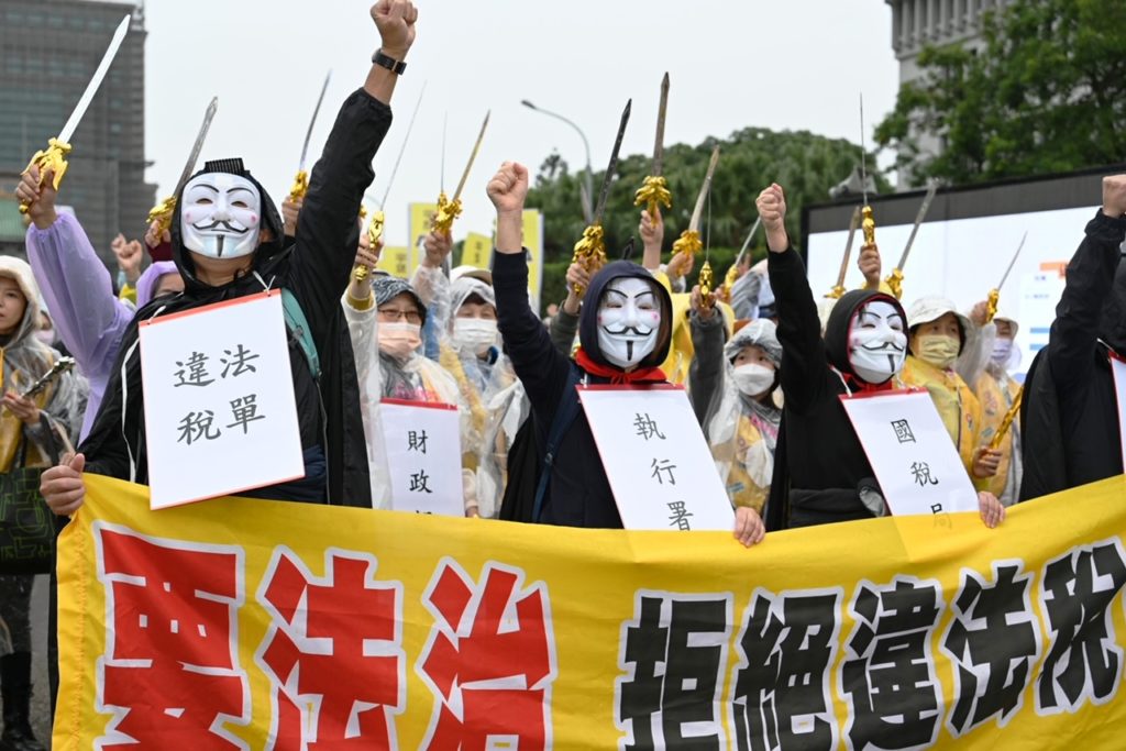 ▲民眾高舉抗議標語,呼籲政府關注法稅正義。(記者晨曦翻攝)